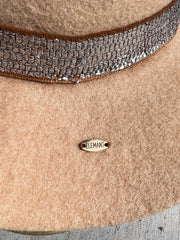 Light beige wool fedora hat with frayed metal silver band and brown underlay. Red agate stone and brown, white and orange feathers attached as well as gold Elemant metal logo on back.