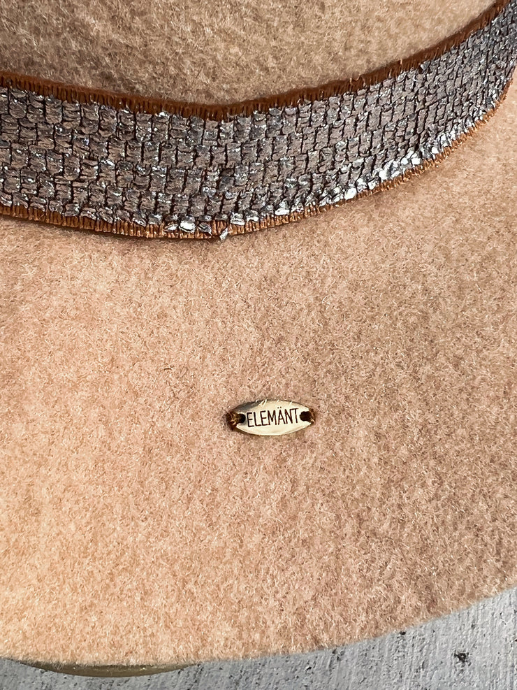 Light beige wool fedora hat with frayed metal silver band and brown underlay. Red agate stone and brown, white and orange feathers attached as well as gold Elemant metal logo on back.