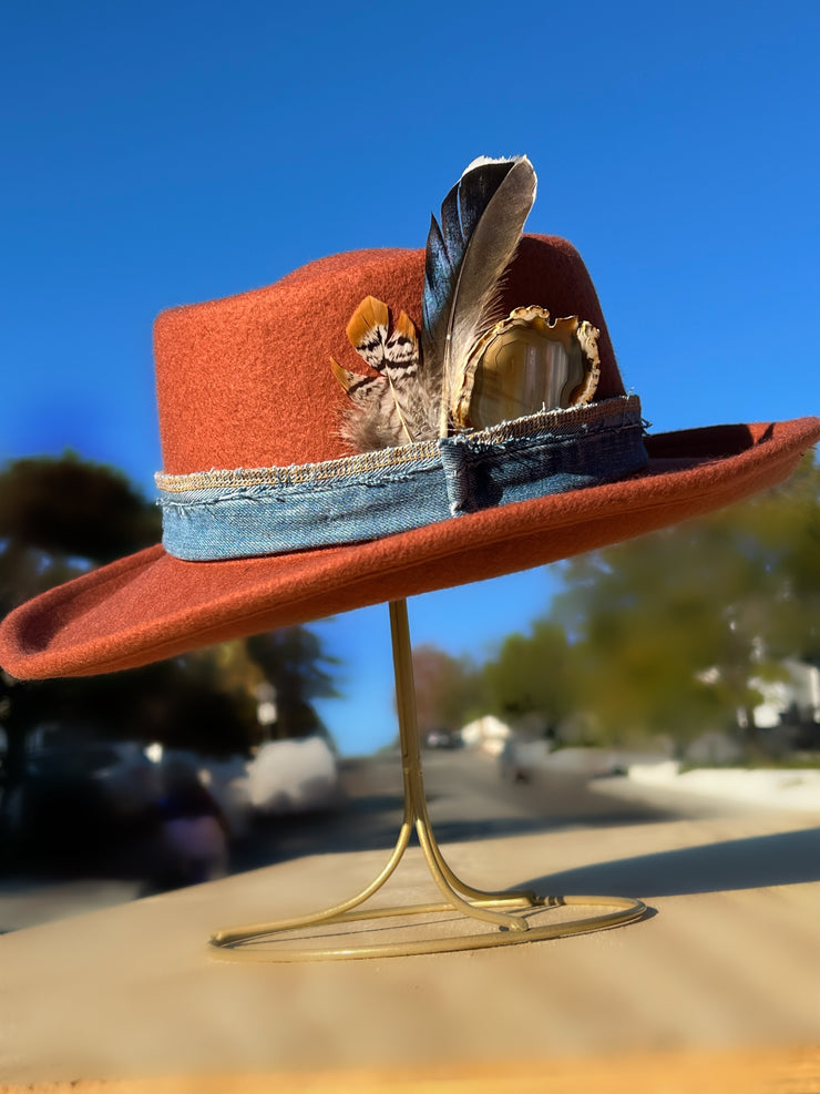 Billy Jean.  Orange wool fedora hat with white/brown Agate slice and feathers in brown, orange, white and blue. Vintage blue denim band and gold Elemant stitched on gold emblem. 