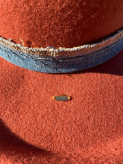 Billy Jean. Orange wool fedora hat with white/brown Agate slice and feathers in brown, orange, white and blue. Vintage blue denim band and gold Elemant stitched on gold emblem.