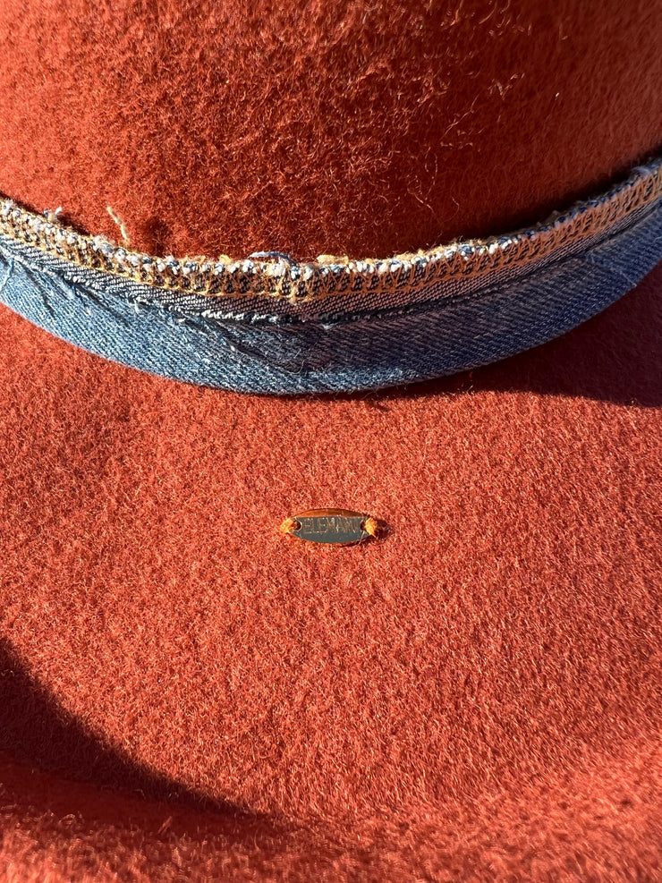 Billy Jean. Orange wool fedora hat with white/brown Agate slice and feathers in brown, orange, white and blue. Vintage blue denim band and gold Elemant stitched on gold emblem.