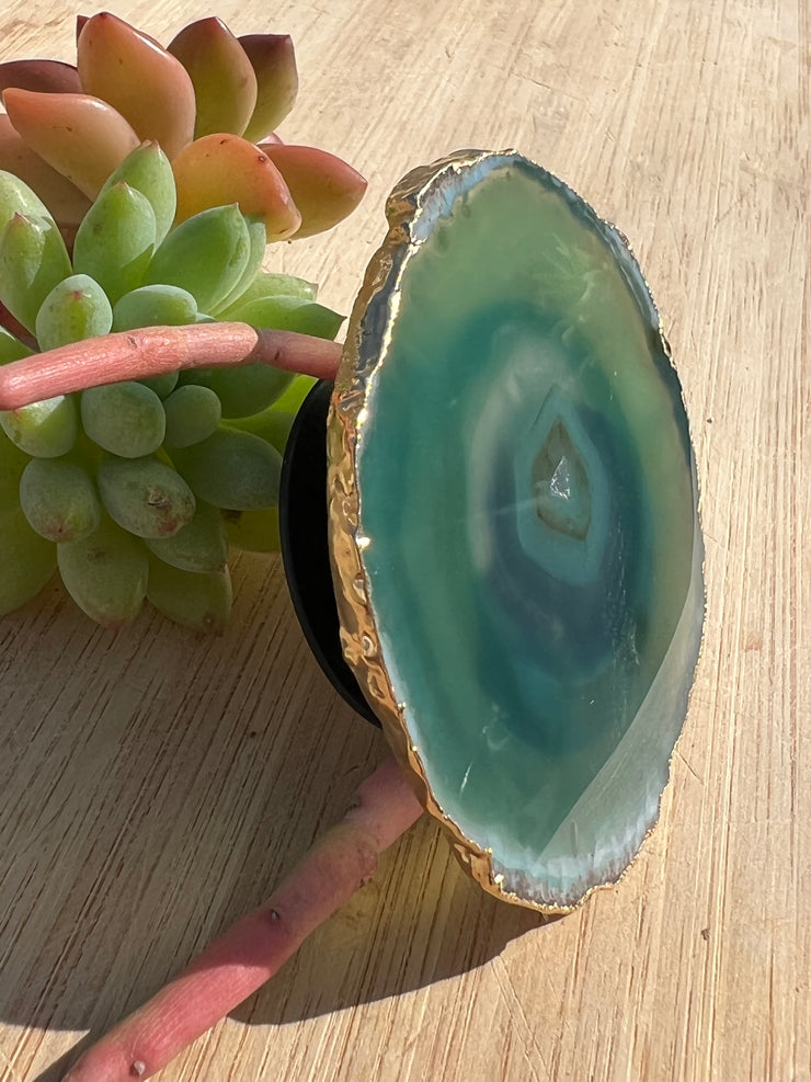 Green Agate pop socket (popsocket) for use with iphone, androids, ipads, smartphones and other small tecnical devices. Used for easy grip of electronics as well as a beautiful phone accessory. It is an attachment that easily tapes onto the back of the device and pops in and out as needed for use. These agate slices are natural and pure agate stones imported from Brazil of the highest quality and beautifylly gold dipped on the rim.