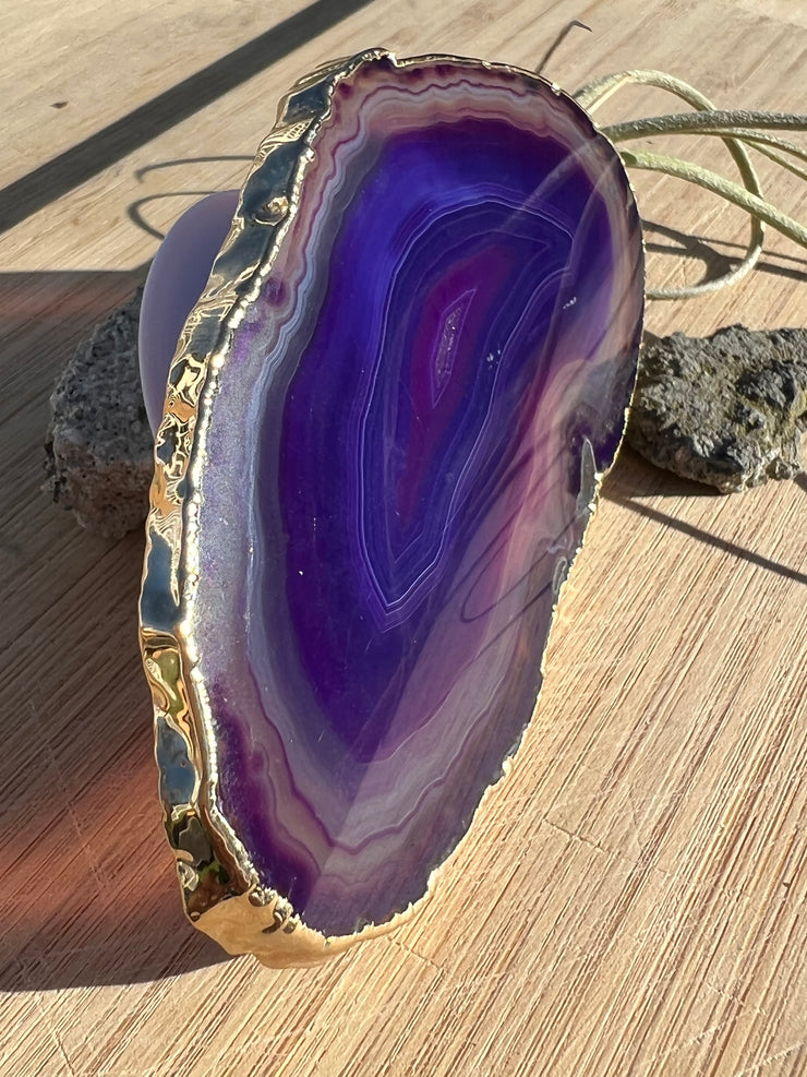 Purple Agate pop socket (popsocket) for use with iphone, androids, ipads, smartphones and other small tecnical devices. Used for easy grip of electronics as well as a beautiful phone accessory. It is an attachment that easily tapes onto the back of the device and pops in and out as needed for use. These agate slices are natural and pure agate stones imported from Brazil of the highest quality and beautifylly gold dipped on the rim.