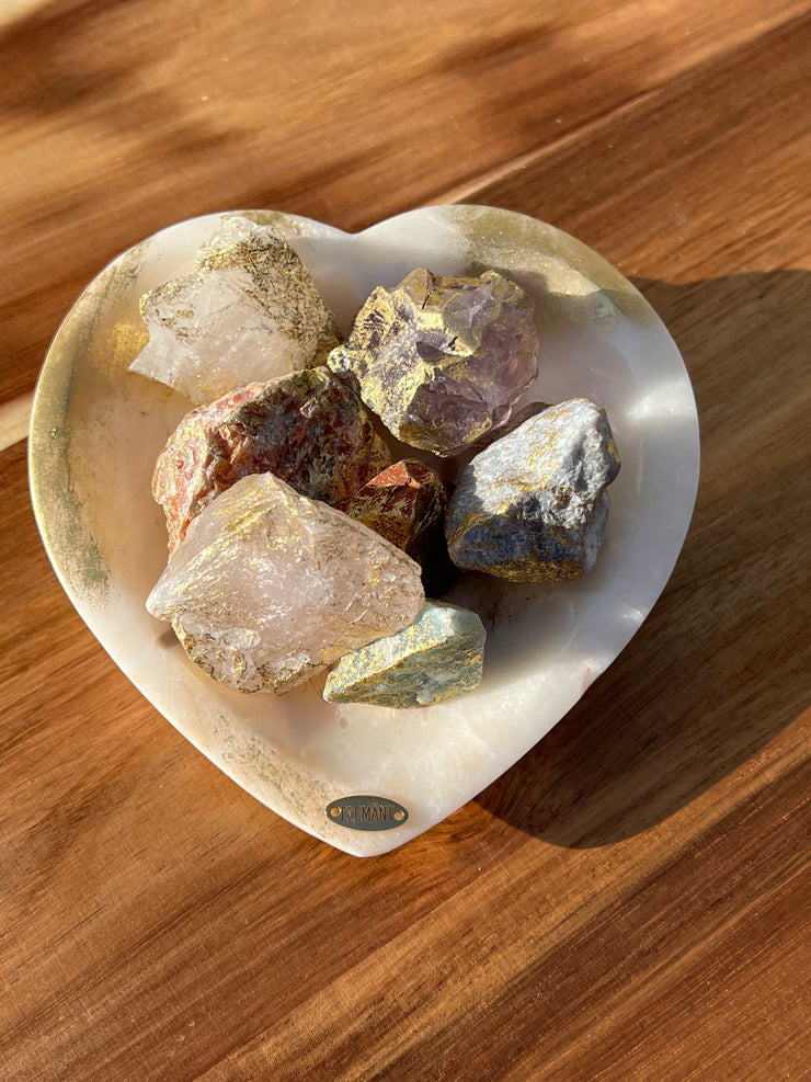 Onyx bowl with 7 different meditation stones inside. White Quartz, Rose Quartz, Green Quartz, Blue Quartz, Red Jasper, Amethyst and Orange Calcite. A gold Elemant logo emblem is attached to the bowl and both the bowl and stones are artfully gold dusted. Includes a note describing each of the meditation stones meaning and benefits.