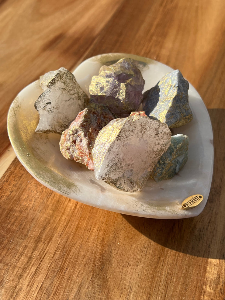 Onyx bowl with 7 different meditation stones inside. White Quartz, Rose Quartz, Green Quartz, Blue Quartz, Red Jasper, Amethyst and Orange Calcite. A gold Elemant logo emblem is attached to the bowl and both the bowl and stones are artfully gold dusted. Includes a note describing each of the meditation stones meaning and benefits.