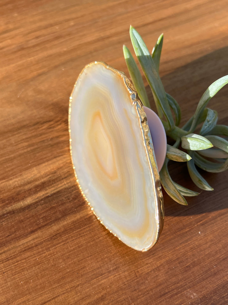 White Agate pop socket (popsocket) for use with iphone, androids, ipads, smartphones and other small tecnical devices. Used for easy grip of electronics as well as a beautiful phone accessory. It is an attachment that easily tapes onto the back of the device and pops in and out as needed for use. These agate slices are natural and pure agate stones imported from Brazil of the highest quality and beautifylly gold dipped on the rim.