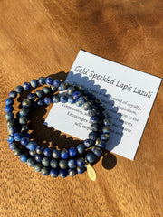 Lightly gold dusted natural Lapis Lazuli beaded bracelets on three stretchy strings of beads with an Elemant logo emblem attached to one of them.  Each set of beads come with a card describing the stones benefits and meaning.