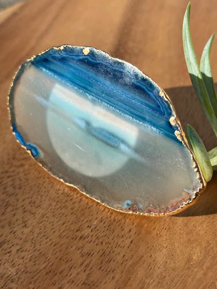 Blue Agate pop socket (popsocket) for use with iphone, androids, ipads, smartphones, and other small tecnical devices. Used for easy grip of electronics as well as a beautiful phone accessory. It is an attachment that easily tapes onto the back of the device and pops in and out as needed for use. These agate slices are natural and pure agate stones imported from Brazil of the highest quality and beautifylly gold dipped on the rim.