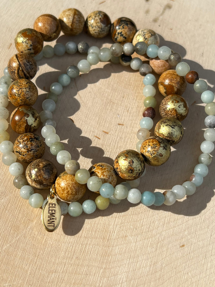Gold speckled natural Jasper stone beads 8mm in size and two natural stone Amazonite string beads in 4mm. Beads come in stretched bracelet bands 19cm (7.5in) length. Elemant logo emblem is attached to the Jasper bead string and all three strings of bracelet beads come detached for easy wear and comfort. 