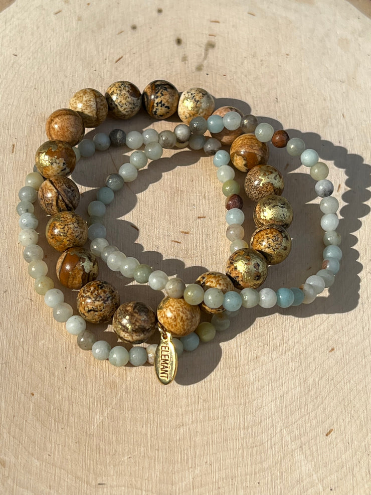 Gold speckled natural Jasper stone beads 8mm in size and two natural stone Amazonite string beads in 4mm.  Beads come in stretched bracelet bands 19cm (7.5in) length.  Elemant logo emblem is attached to the Jasper bead string and all three strings of bracelet beads come detached for easy wear and comfort. 