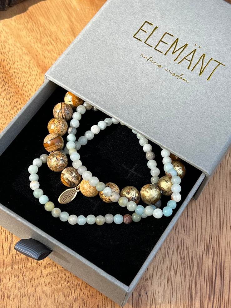 Gold speckled natural Jasper stone beads 8mm in size and two natural stone Amazonite string beads in 4mm. Beads come in stretched bracelet bands 19cm (7.5in) length. Elemant logo emblem is attached to the Jasper bead string and all three strings of bracelet beads come detached for easy wear and comfort.
