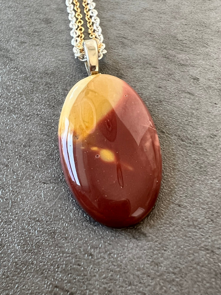 Red Mookaite Jasper necklace pendant with beautful color variations on gold and silver chains in equal lengths and a silver Elemant emblem attached at the clasp.