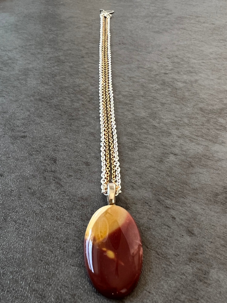 Red Mookaite Jasper necklace pendant with beautful color variations on gold and silver chains in equal lengths and a silver Elemant emblem attached at the clasp.