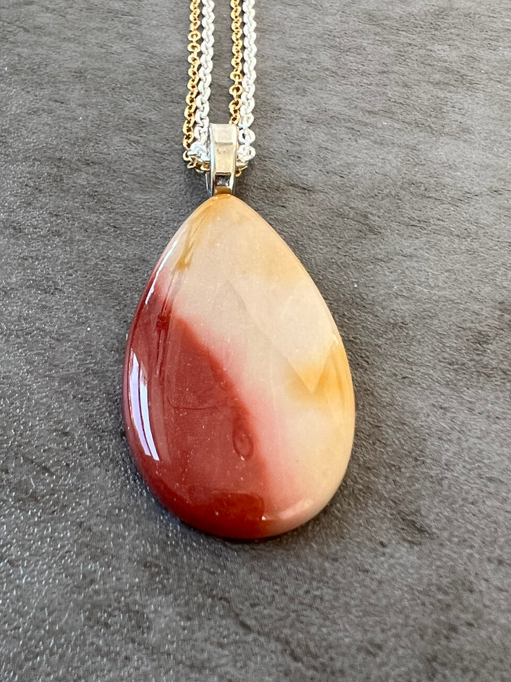 Red Mookaite Jasper necklace pendant with beautful color variations on gold and silver chains in equal lengths and a silver Elemant emblem attached at the clasp.
