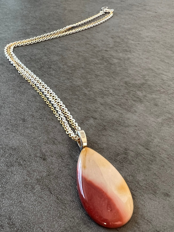 Red Mookaite Jasper necklace pendant with beautful color variations on gold and silver chains in equal lengths and a silver Elemant emblem attached at the clasp.