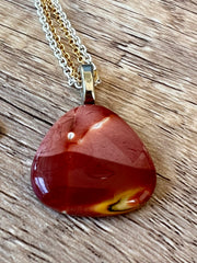 Red Mookaite Jasper necklace pendant with beautful color variations on gold and silver chains in equal lengths and a silver Elemant emblem attached at the clasp.
