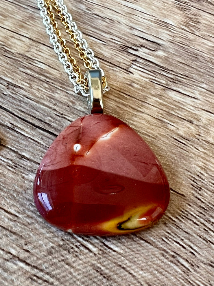 Red Mookaite Jasper necklace pendant with beautful color variations on gold and silver chains in equal lengths and a silver Elemant emblem attached at the clasp.