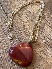 Red Mookaite Jasper necklace pendant with beautful color variations on gold and silver chains in equal lengths and a silver Elemant emblem attached at the clasp.