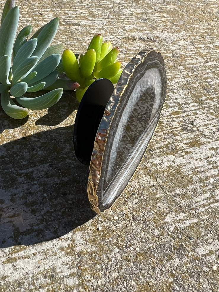 Black Agate pop socket (popsocket) for use with iphone, androids, ipads, and other small tecnical devices. Used for easy grip of electronics as well as a beautiful phone accessory. It is an attachment that easily tapes onto the back of the device and pops in and out as needed for use. These agate slices are natural and pure agate stones imported from Brazil of the highest quality and beautifylly gold dipped on the rim.