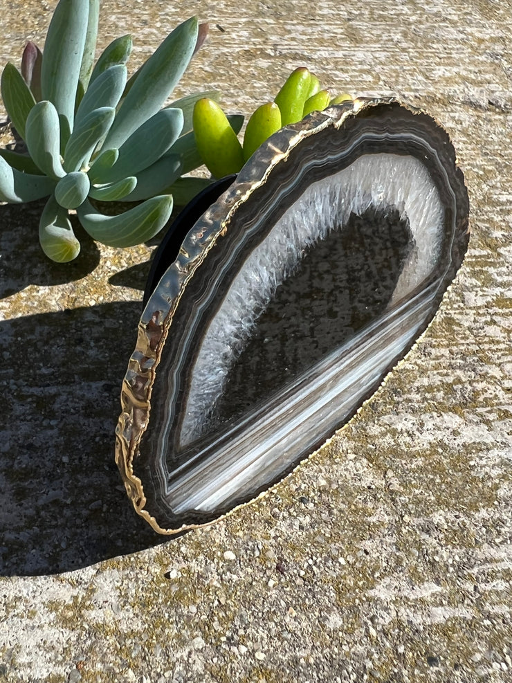 Black Agate pop socket (popsocket) for use with iphone, androids, ipads, and other small tecnical devices. Used for easy grip of electronics as well as a beautiful phone accessory. It is an attachment that easily tapes onto the back of the device and pops in and out as needed for use. These agate slices are natural and pure agate stones imported from Brazil of the highest quality and beautifylly gold dipped on the rim.