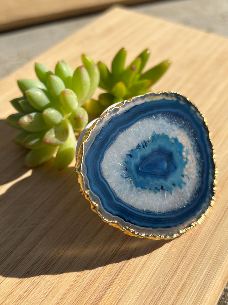 Blue Agate pop socket (popsocket) for use with iphone, androids, ipads, smartphones, and other small tecnical devices. Used for easy grip of electronics as well as a beautiful phone accessory. It is an attachment that easily tapes onto the back of the device and pops in and out as needed for use. These agate slices are natural and pure agate stones imported from Brazil of the highest quality and beautifylly gold dipped on the rim.